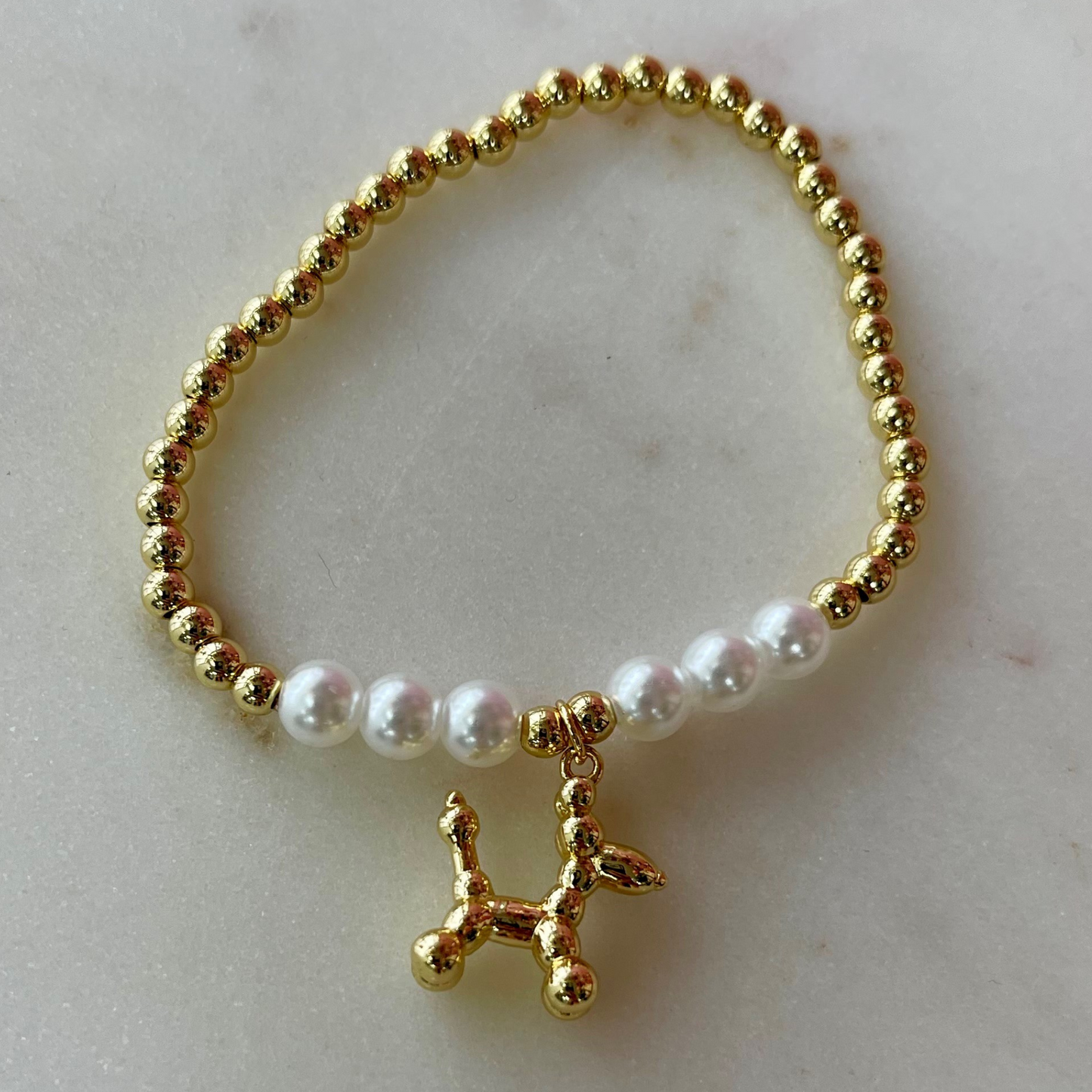 gold and pearl band bracelet with a gold balloon shaped dog