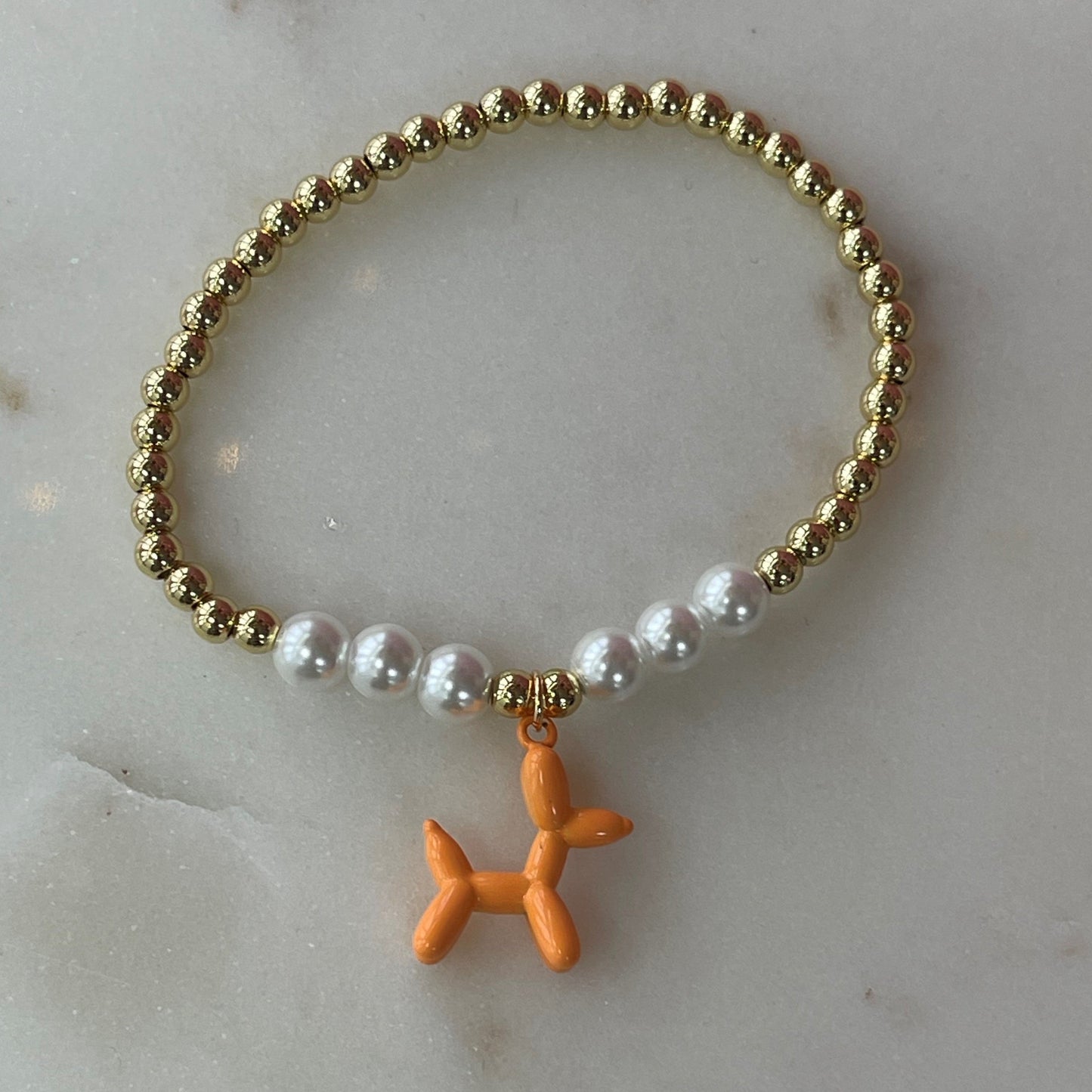 gold and white pearl band bracelet with an orange balloon shaped dog