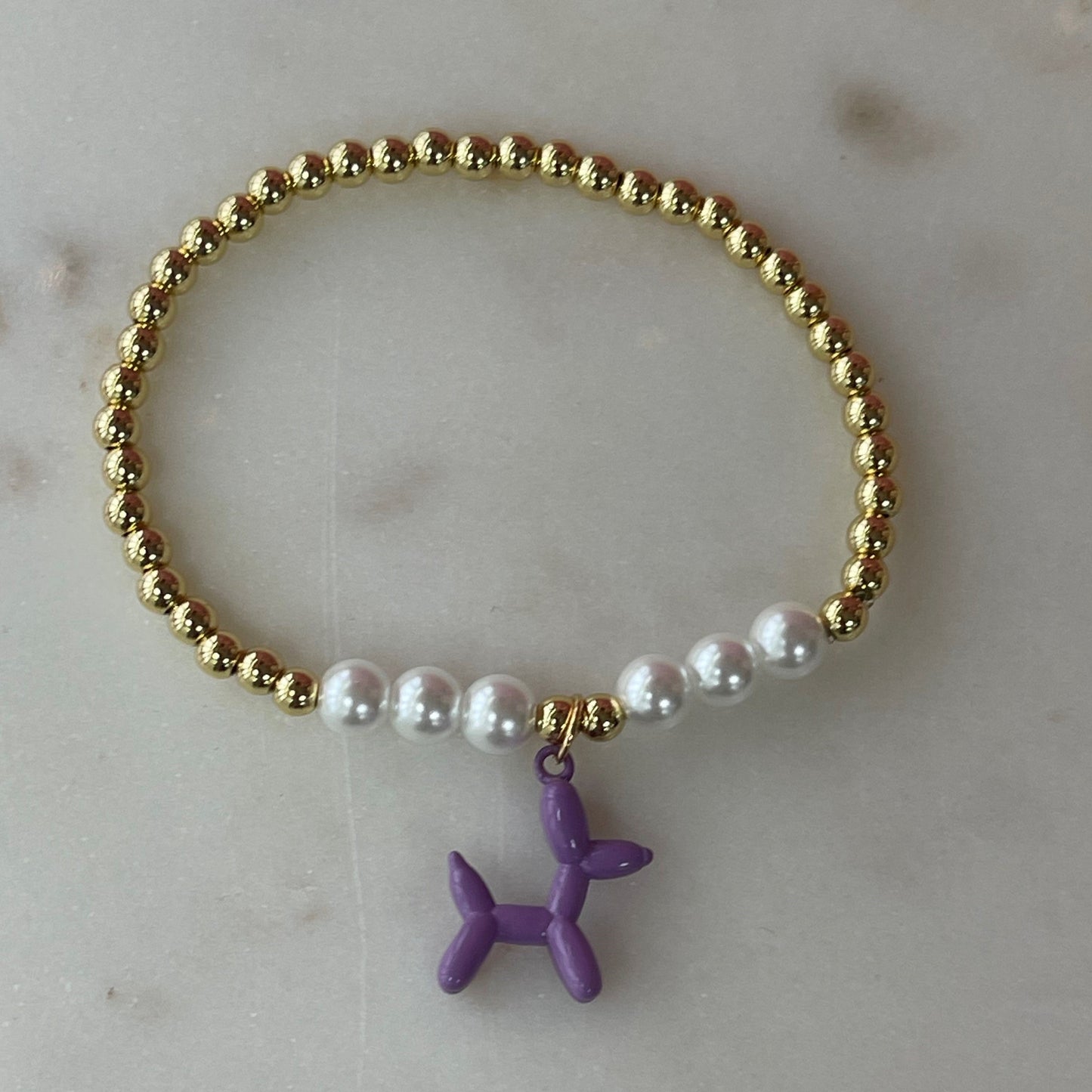 gold and white pearl band bracelet with a purple balloon shaped dog