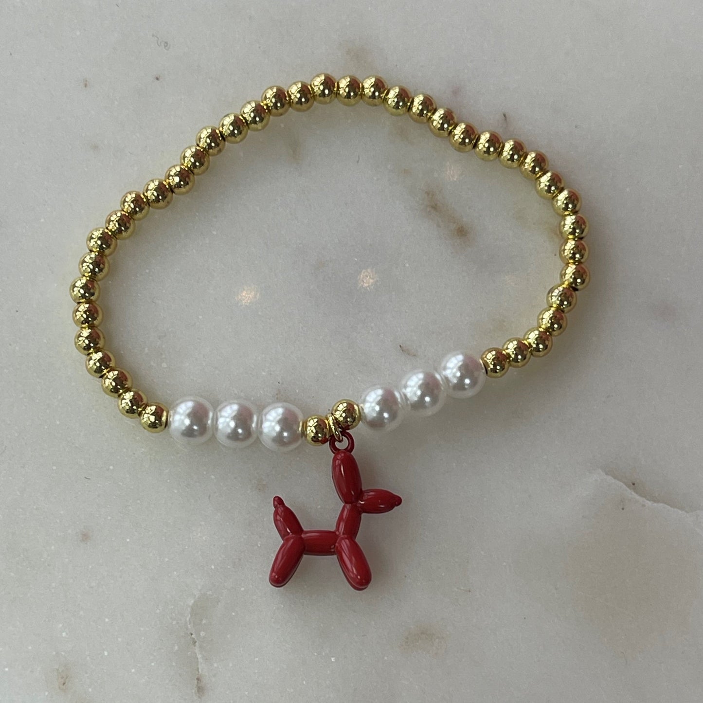 gold and pearl band bracelet with a red balloon shaped dog